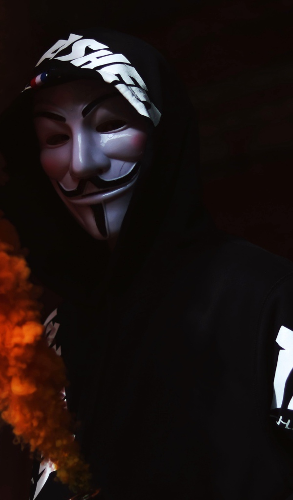 Мужчина в маске анонимуса с дымовой шашкой в руке