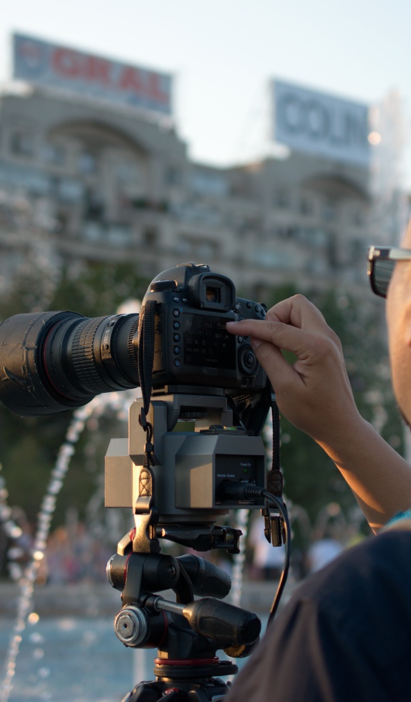 Мужчина снимает на камеру фонтан в парке