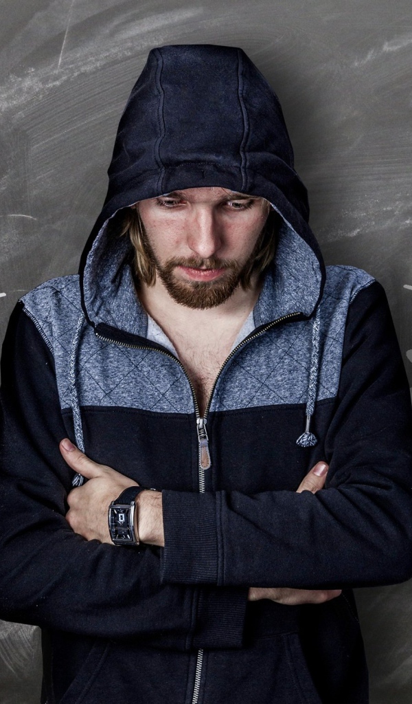 Мужчина с часами на руке грустит у стены