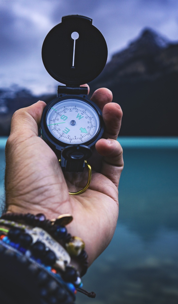 Компас в руке у мужчины на фоне гор 