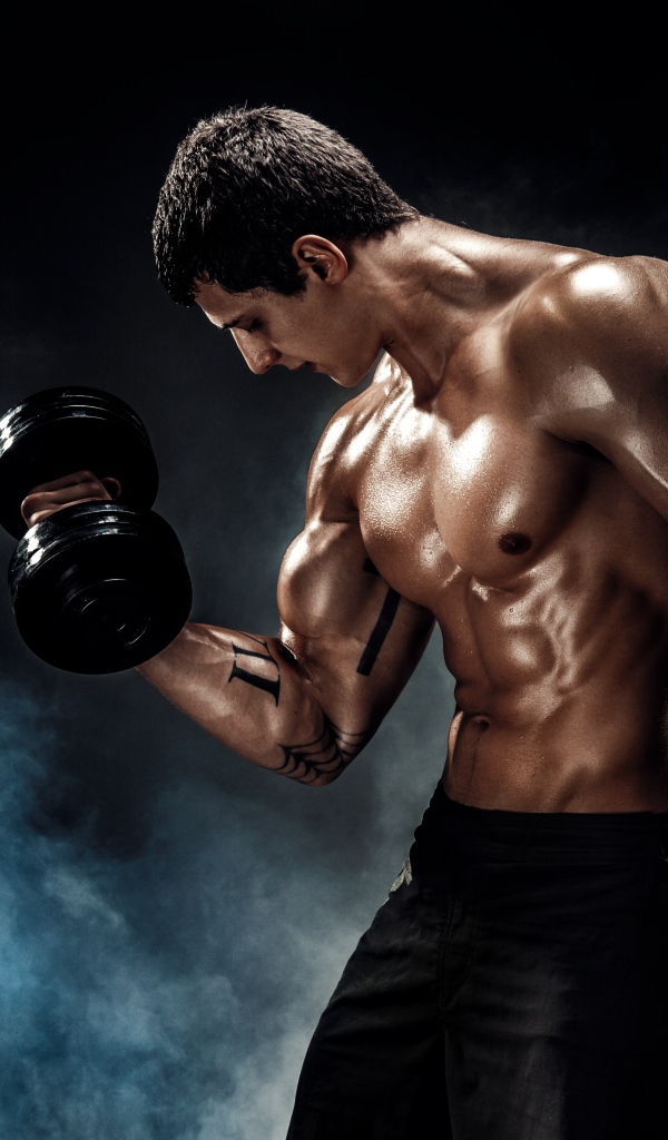 Накаченный мужчина с гантелей в руке в дыму 