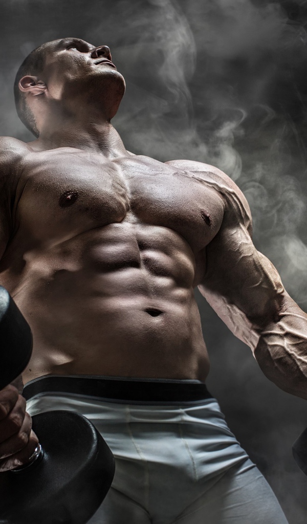 Мужчина бодибилдер с тяжелыми гантелями в руках