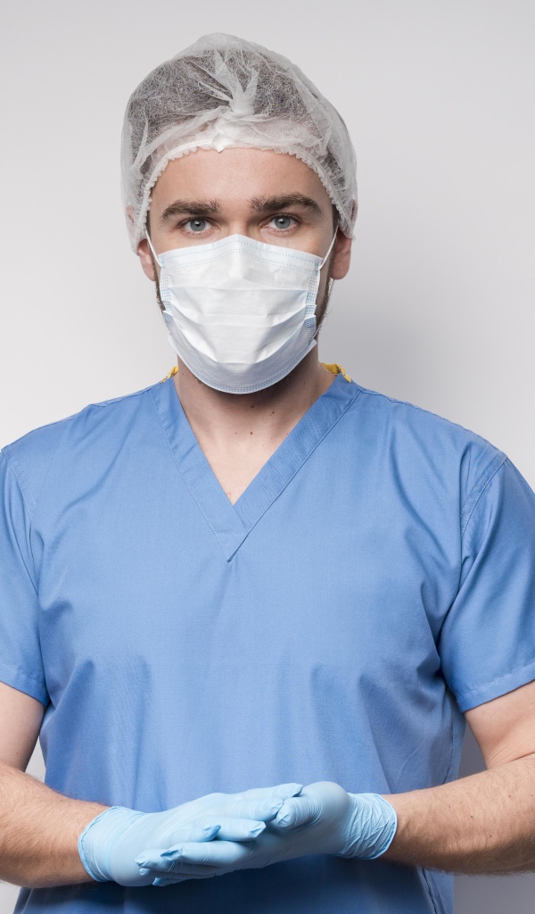 Male doctor in mask and gloves on gray background
