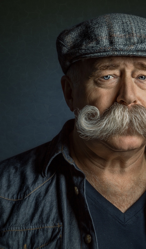 Мужчина в кепке с большими усами на лице 