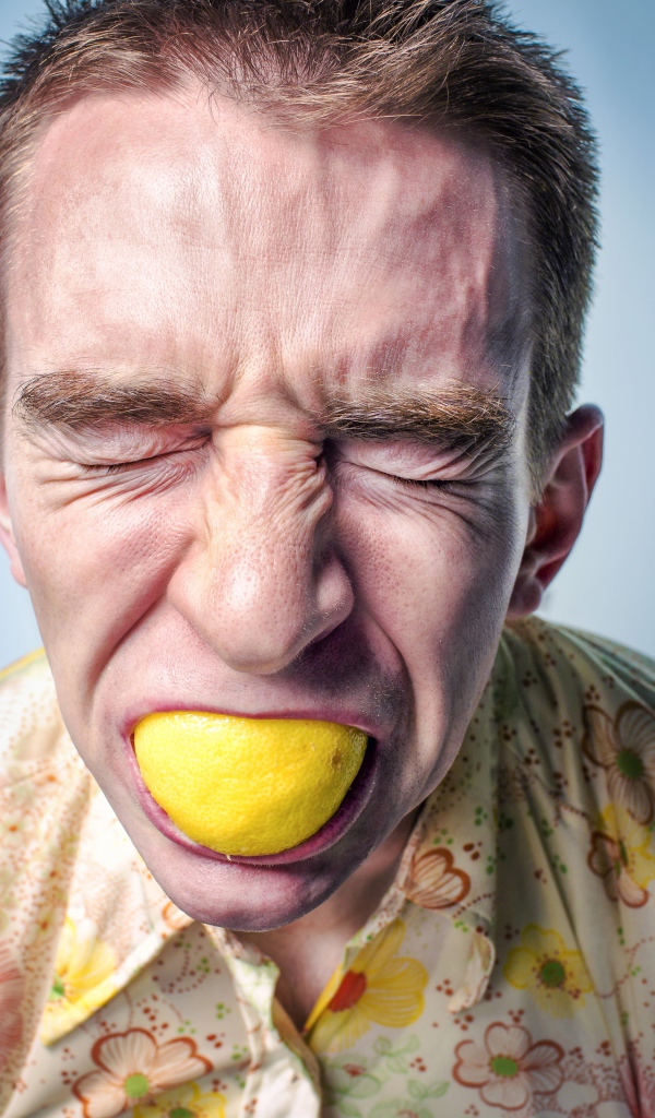 Мужчина с закрытыми глазами ест лимон 