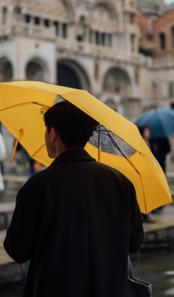 Мужчина с желтым зонтом в городе 