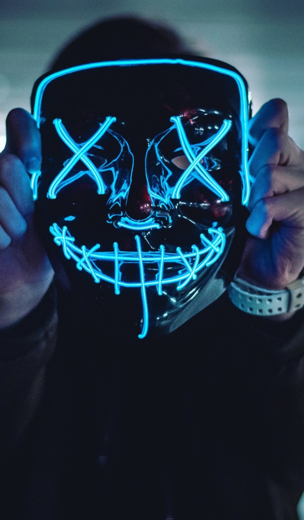 Неоновая маска анонима в руках у парня 
