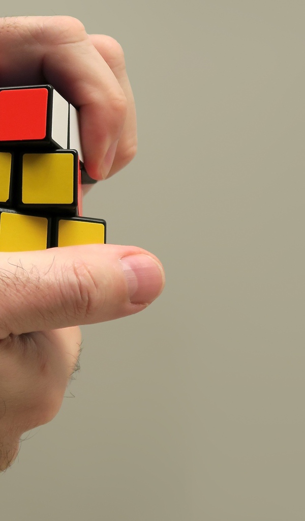 Кубик Рубика в руках мужчины на сером фоне