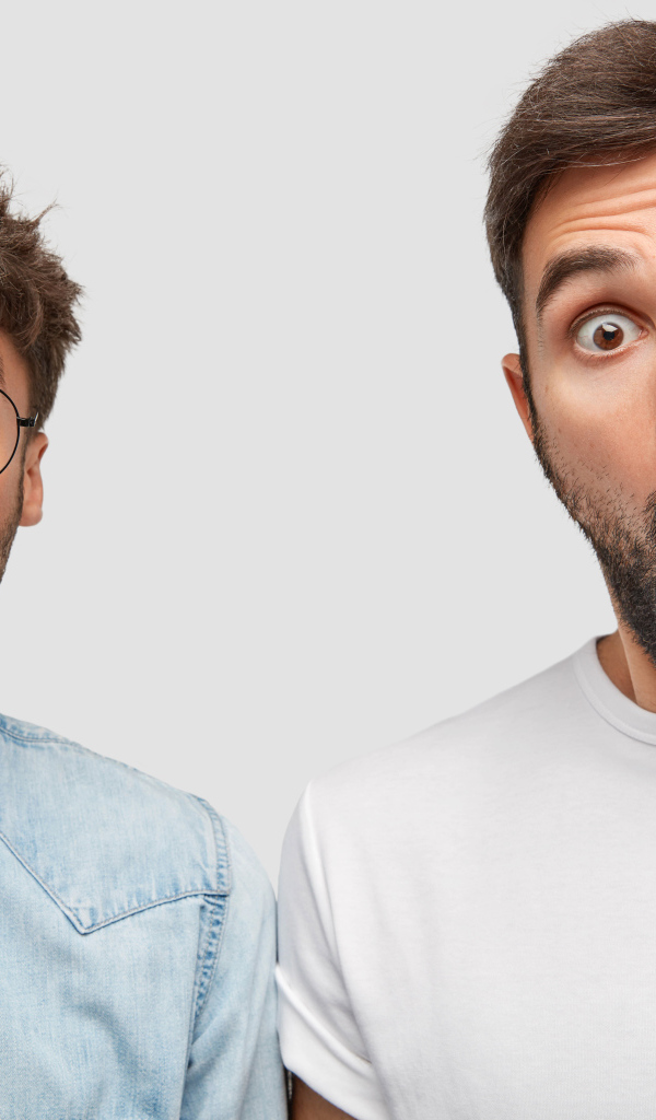 Два удивленных мужчины на сером фоне