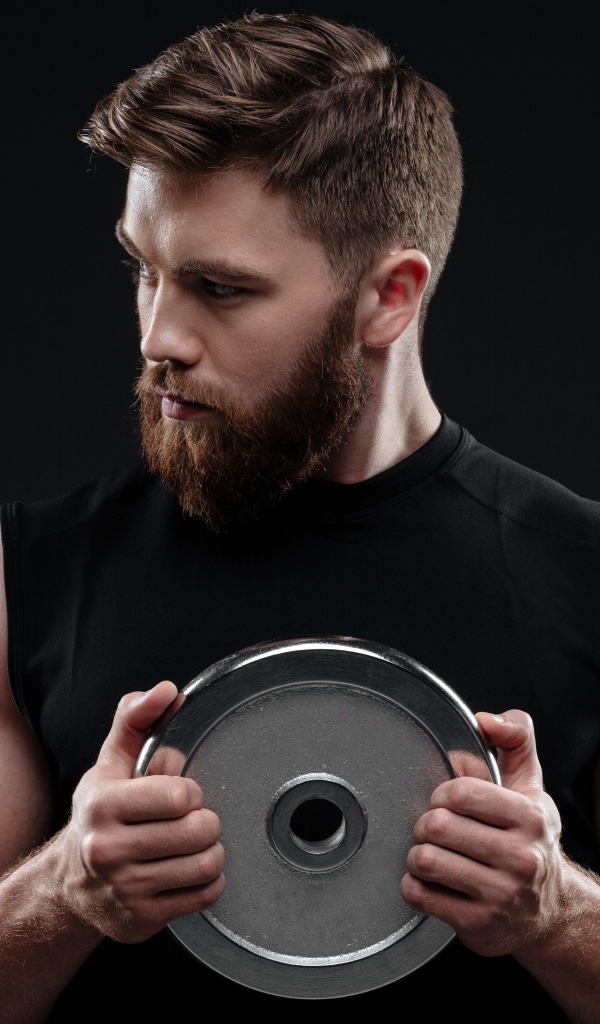 Молодой накаченный парень с железным диском на черном фоне