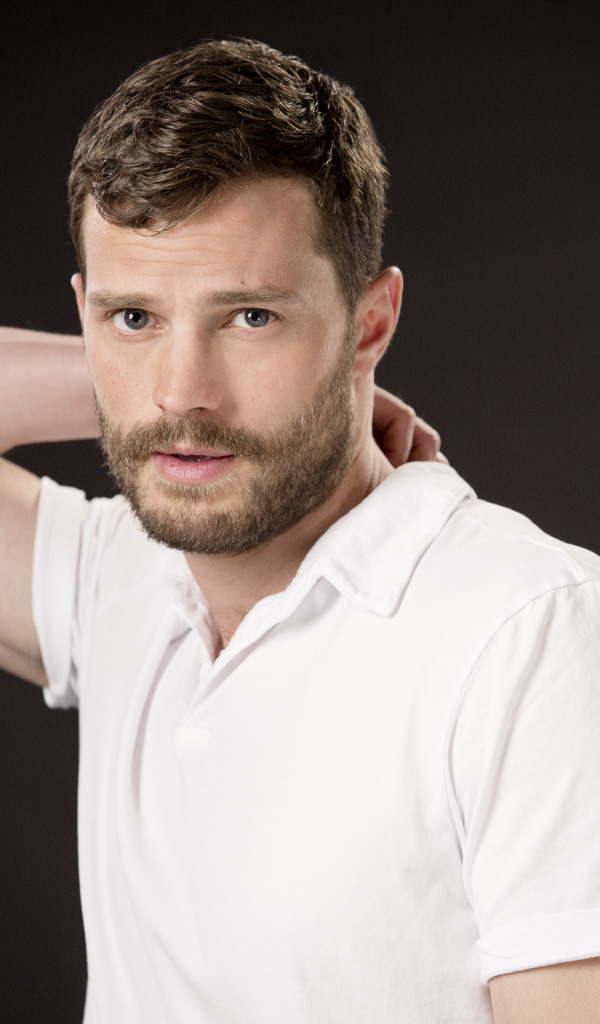 Актер Джейми Дорнан в белой рубашке на коричневом фоне