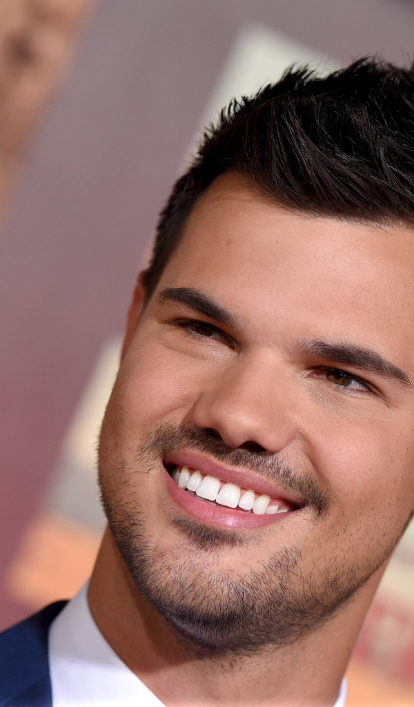 Улыбающийся молодой мужчина, актер Тэйлор Лотнер