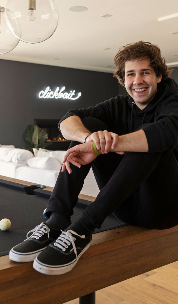 Молодой блогер, юморист  Дэвид Добрик сидит на столе