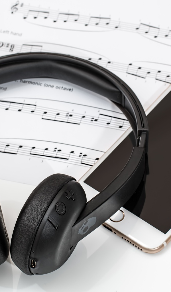 Наушники на столе с нотами и смартфоном