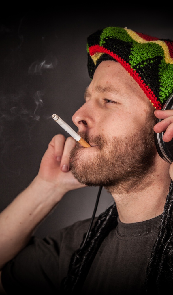 Мужчина растаман в наушниках с сигаретой 