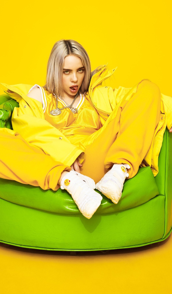 Певица Билли Айлиш сидит в кресле на желтом фоне