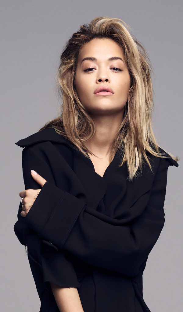 Певица Рита Ора в черном наряде на сером фоне