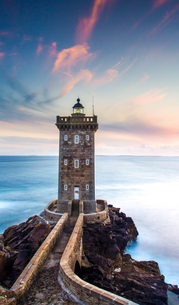 Большой маяк на фоне неба на берегу утеса 