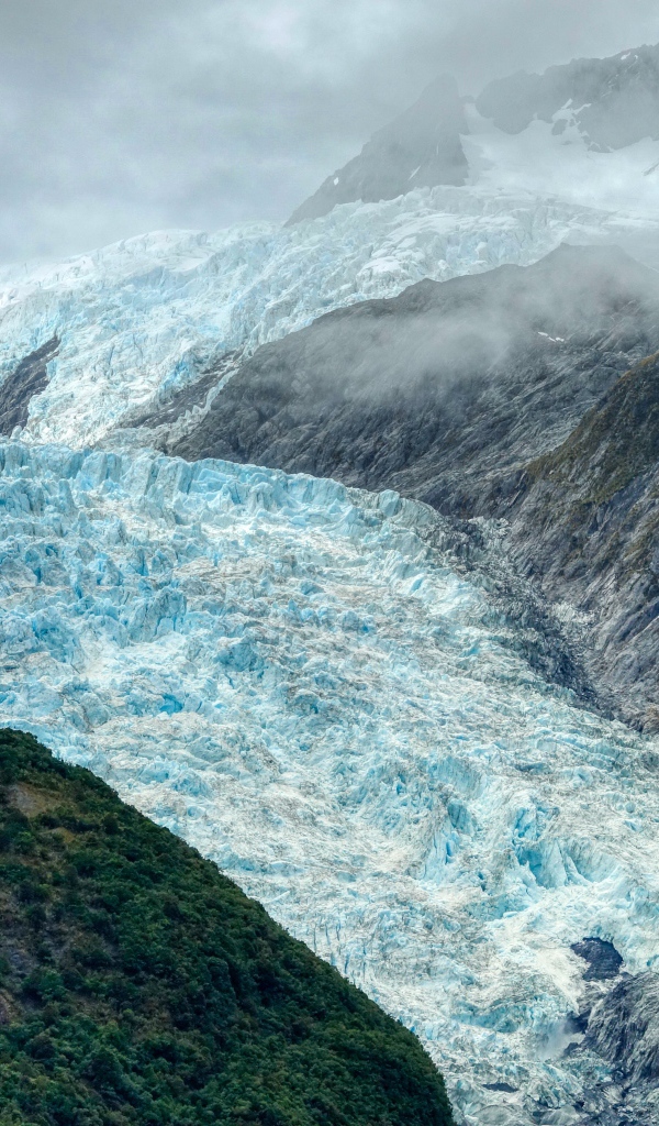Голубой ледник между скал под грозовым небом