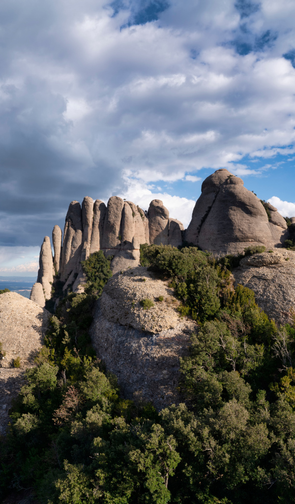 Каменные глыбы под голубым небом с грозовыми облаками 