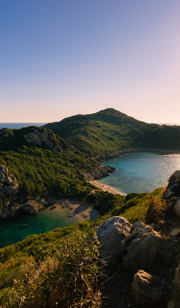 Яркое солнце за скалой у тихого моря