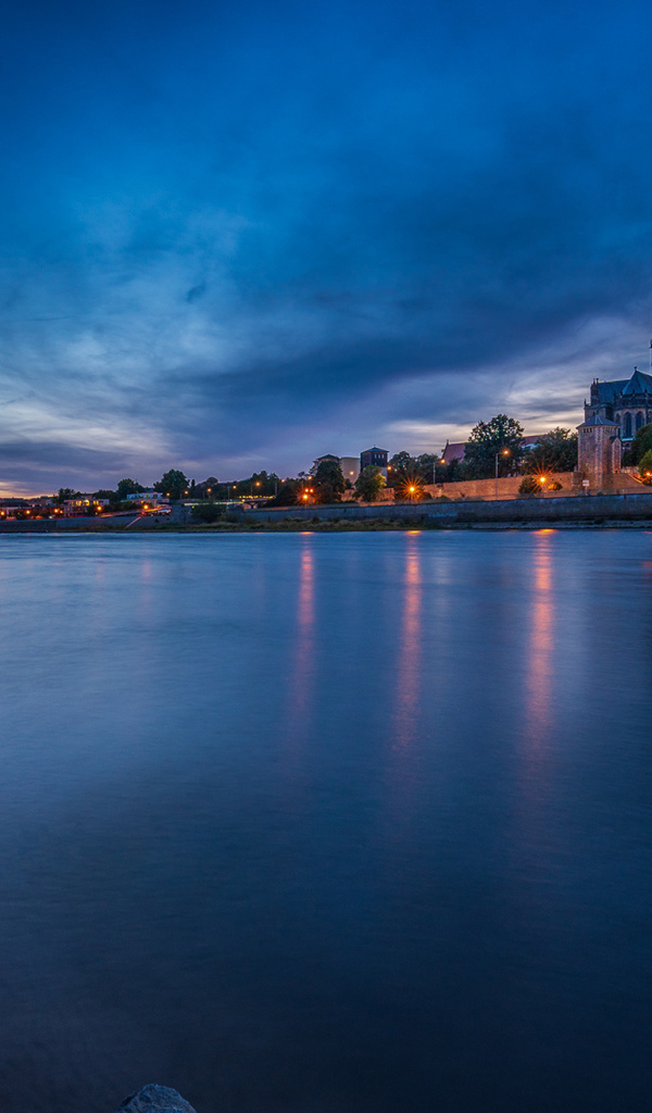 Замок у реки на фоне неба в сумерках 