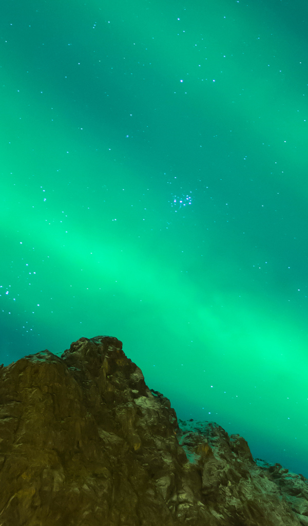 Green aurora borealis over a cliff in the sky