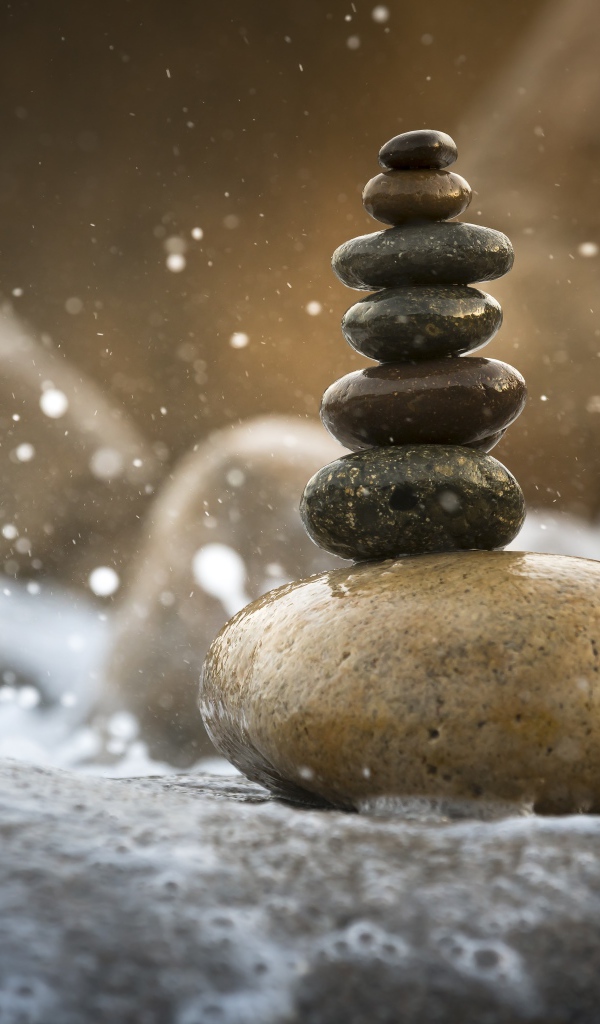 Гладкие мокрые камни в белой морской пене 