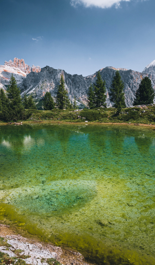 Озеро у заснеженных гор под небом с белыми облаками