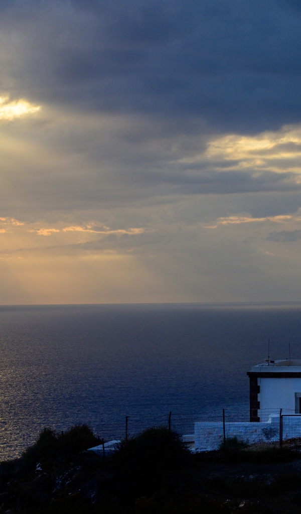 Белый маяк на берегу в лучах солнца у моря 