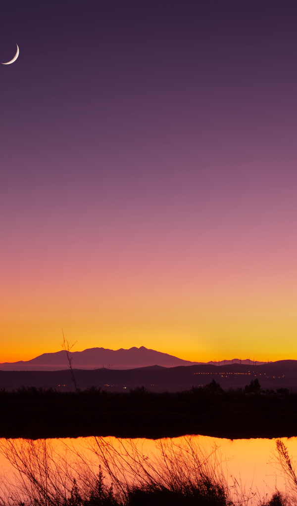Молодой месяц в небе над озером ночью 