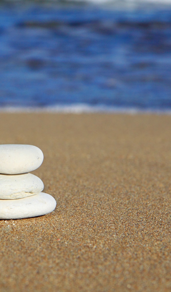 Круглые белые камни на желтом песке 