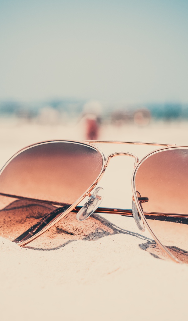 Солнечные очки лежат на горячем песке 