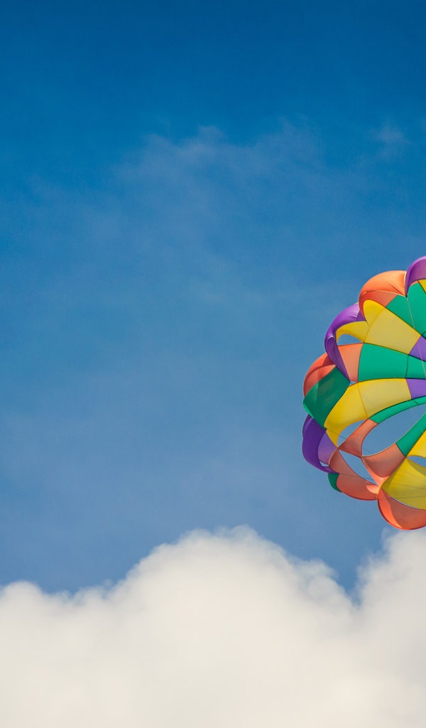 Парашют в голубом небе с белыми облаками