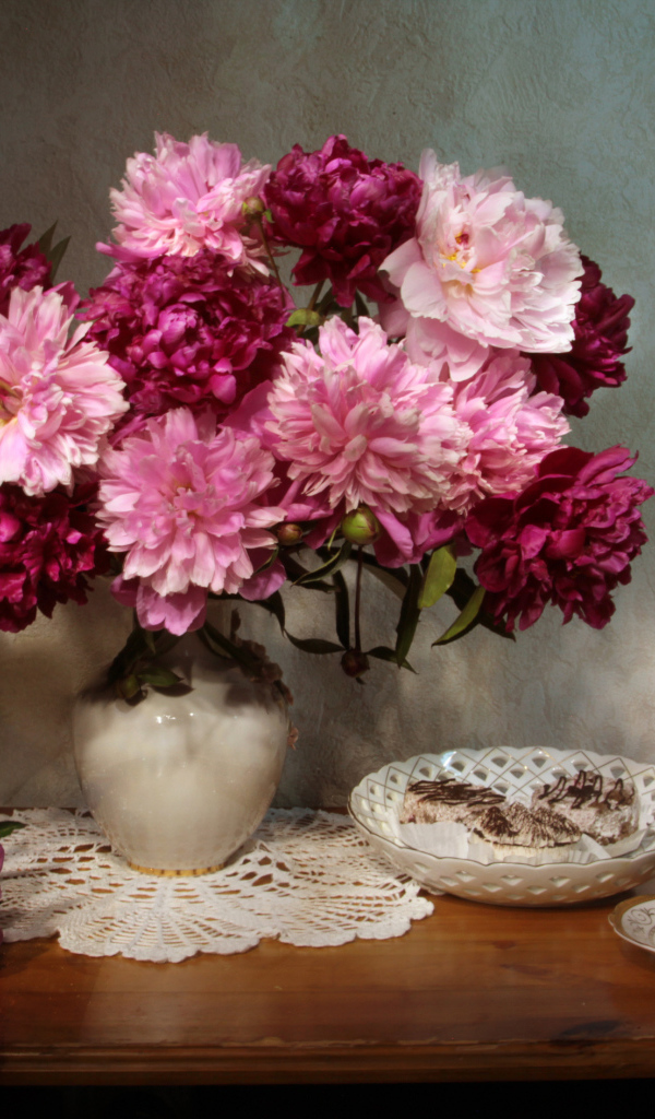 Большой букет розовых пионов в вазе на столе 