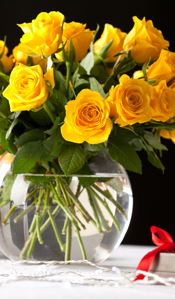 Большой букет желтых роз в вазе на столе с фужерами