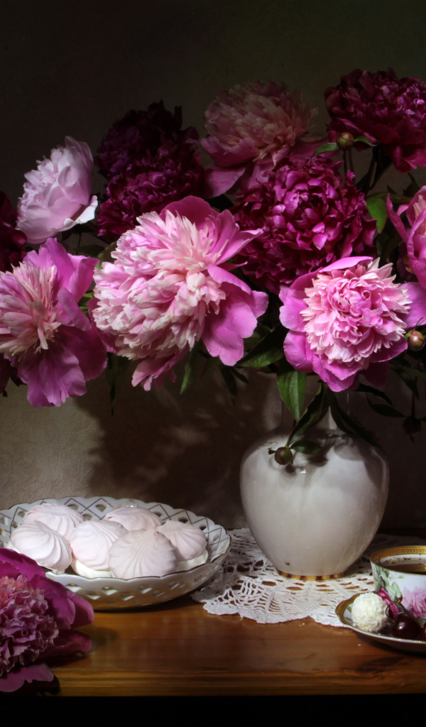 Красивый букет пионов в вазе на столе с зефиром