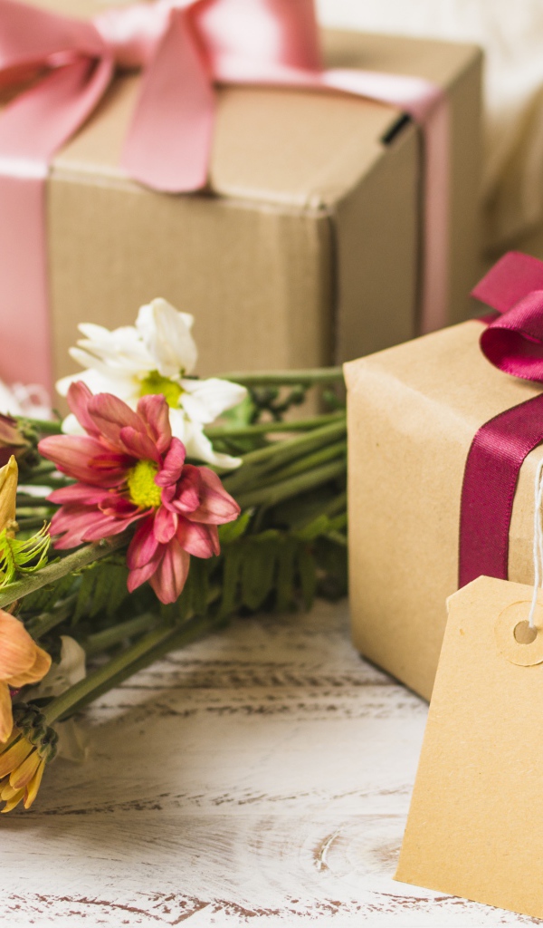 Букет разноцветных хризантем с подарками на столе 