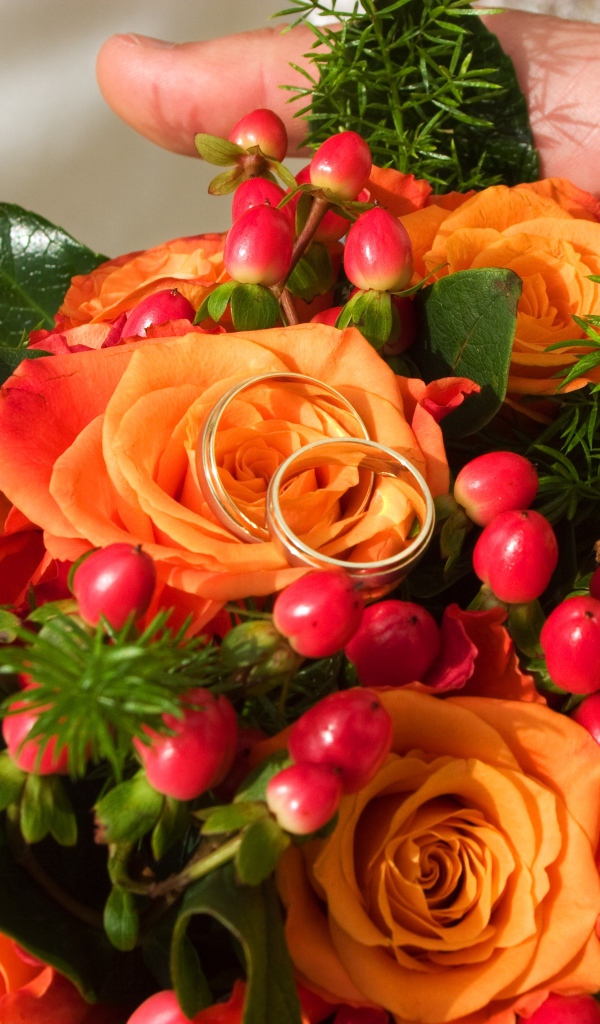 Букет оранжевых роз с красными ягодами и обручальными кольцами