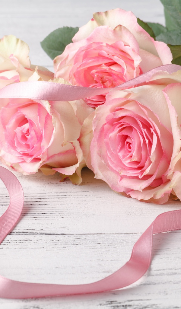 Букет розовых роз с лентой на белом столе 