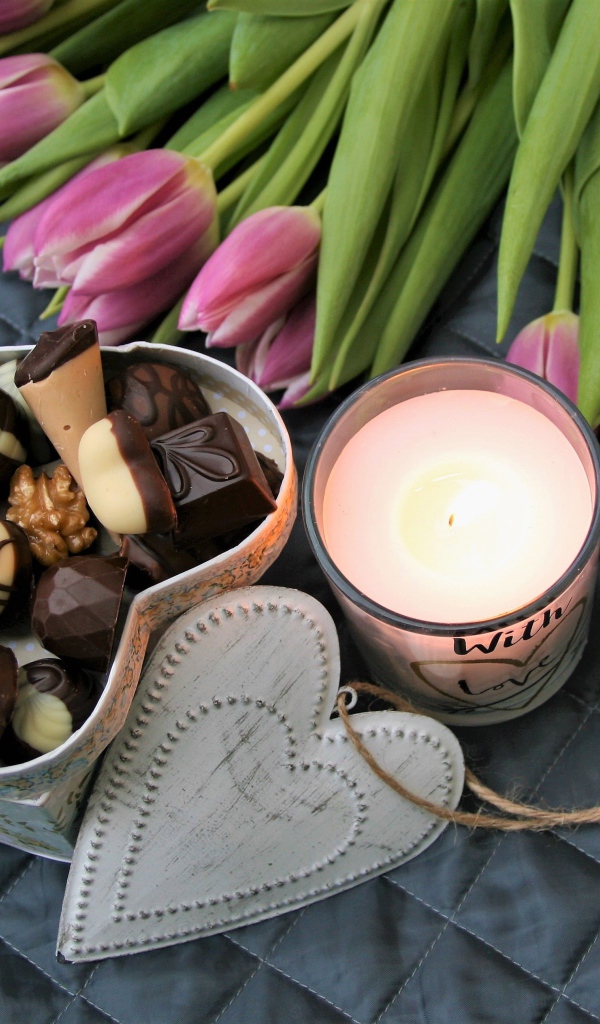 Букет розовых тюльпанов на кровати со свечой и коробкой конфет