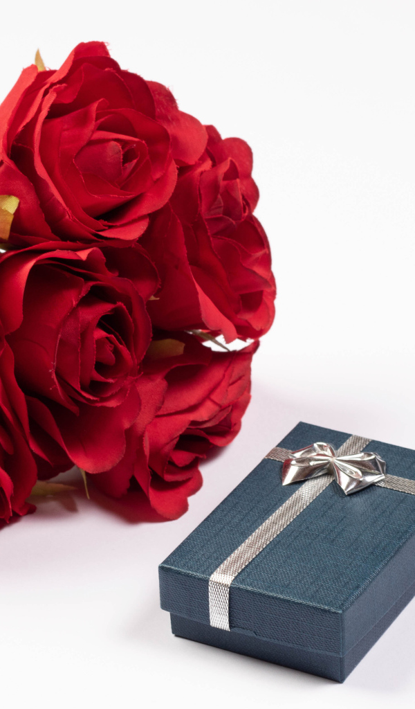 Букет красных искусственных роз с подарком на белом фоне