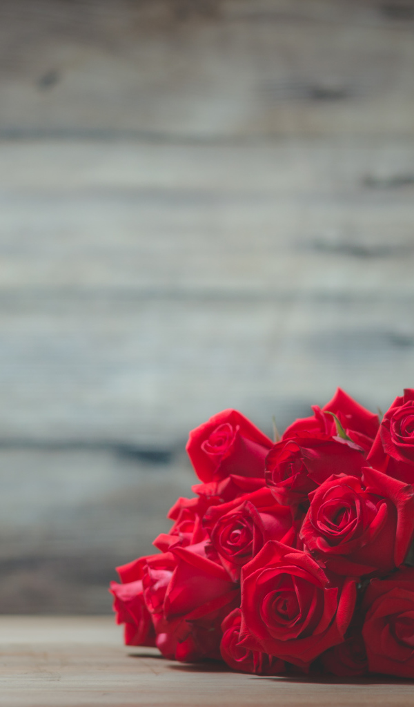 Букет красных роз на фоне деревянной стены 