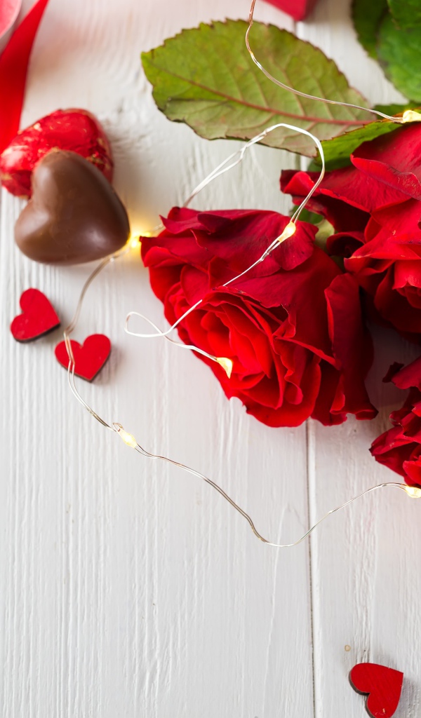 Букет красных роз с конфетами на столе