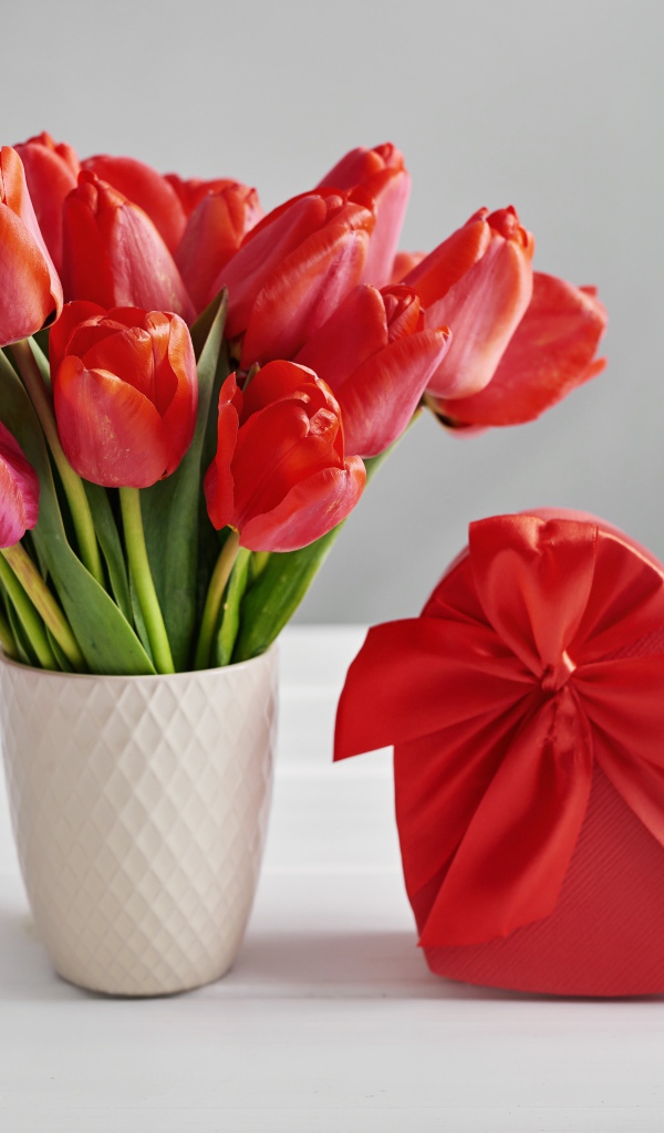 Букет красных тюльпанов на столе с коробкой в форме сердца