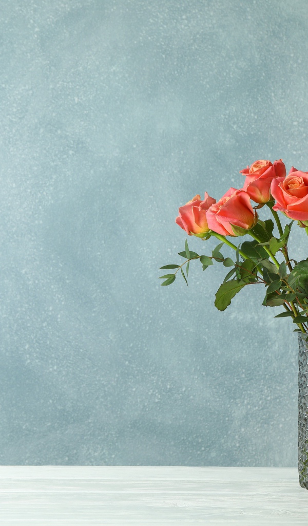 Букет роз в стеклянной вазе на сером фоне
