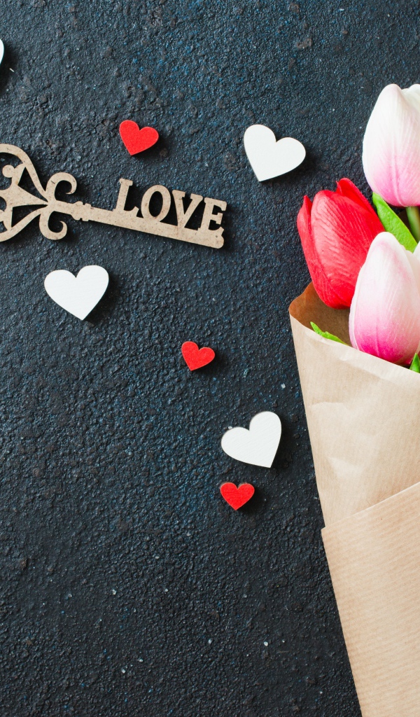 Букет тюльпанов в бумаге на черном фоне с ключом