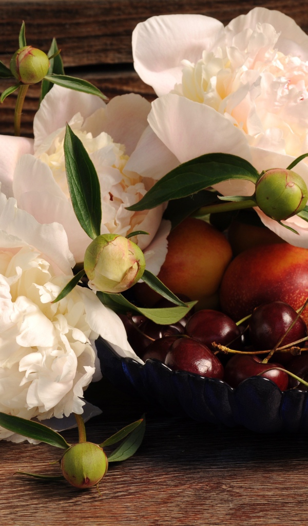 Букет белых пионов на столе с нектарином и черешней