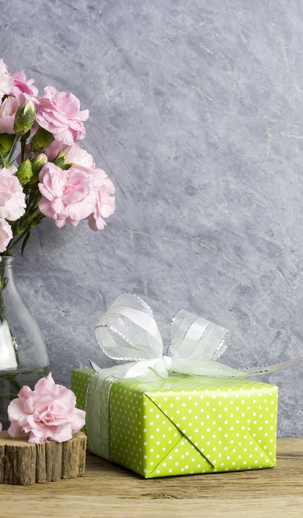 Розовые гвоздики с подарком на сером фоне