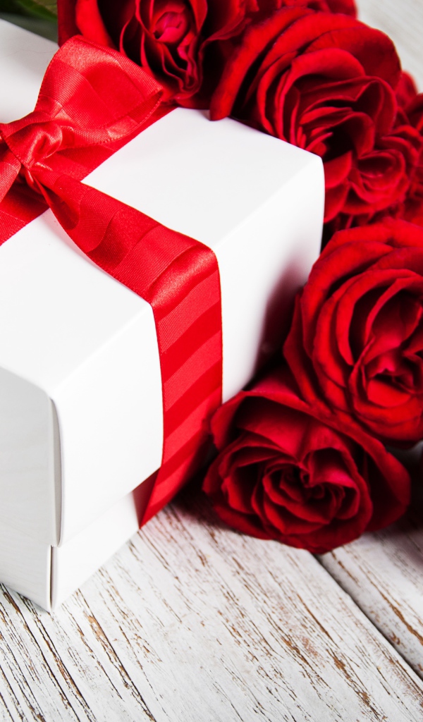 Красные розы на столе с подарком с красной лентой